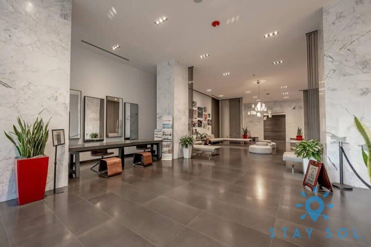 A spacious lobby with a modern design, featuring a reception desk, seating area, and a large mirror wall.