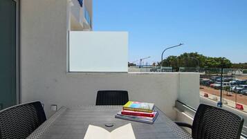 Un balcon avec une table, des chaises et un livre.
