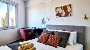 Un dormitorio moderno con una cama grande, un escritorio y una ventana.