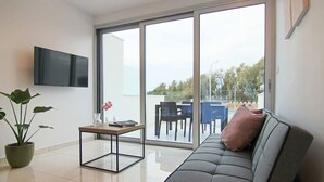 Un soggiorno moderno con un divano grigio, un tavolino, una pianta in vaso e una TV a parete.