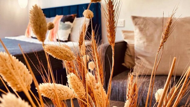 A room with a bed, pillows, and a vase with wheat stalks. - Phaedrus Living: Seaside Luxury Flat Athina 118 (Paphos)