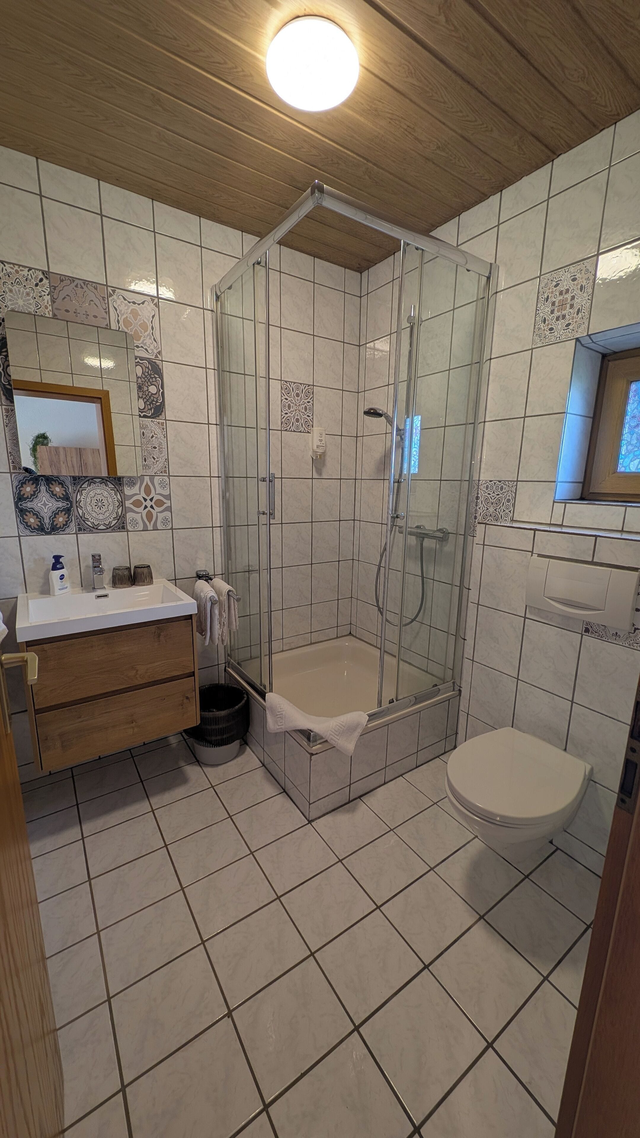 Un baño con ducha, inodoro y tocador con espejo.