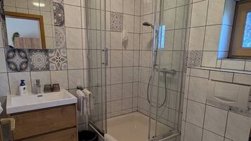 Un baño con ducha, inodoro y tocador con espejo.