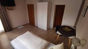 A hotel room with a bed, a desk, a chair, a wardrobe, and a television.