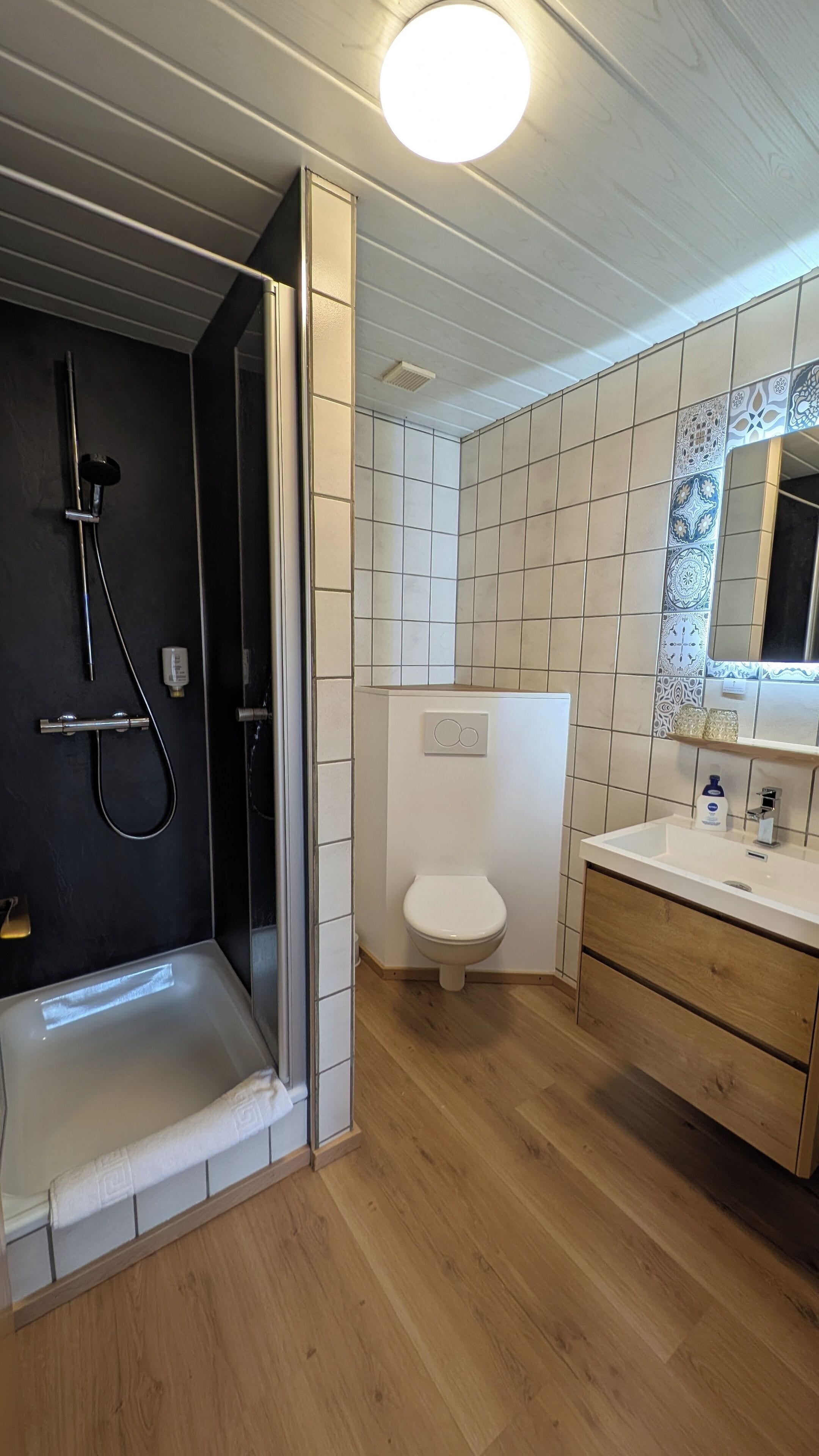 Une salle de bain moderne dotée d’une douche à l’italienne, de toilettes et d’un meuble-lavabo avec un miroir.