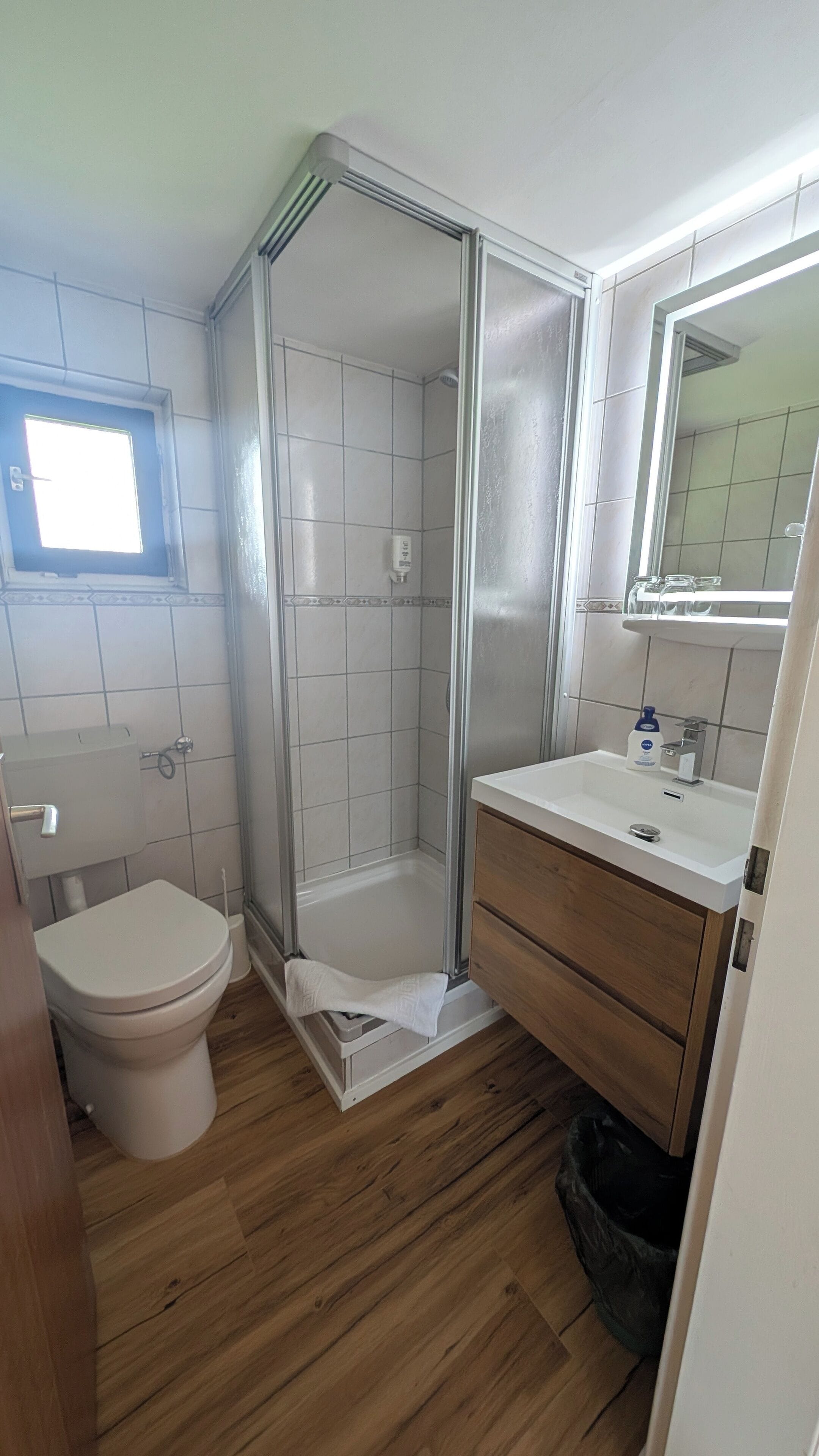 Un baño con inodoro, cabina de ducha, lavabo y espejo.