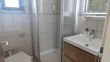 Un baño con inodoro, cabina de ducha, lavabo y espejo.