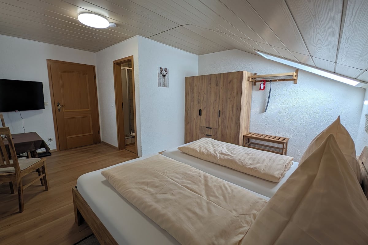 A room with a bed, wooden furniture, a TV, and a wardrobe.