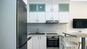 Une cuisine moderne avec des armoires blanches, un réfrigérateur en acier inoxydable, un four et un évier.