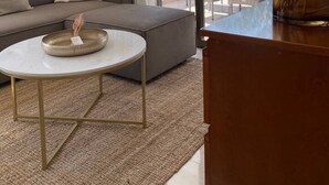 Una sala de estar moderna con un sofá, una mesa redonda de centro y vistas al exterior a través de amplios ventanales.