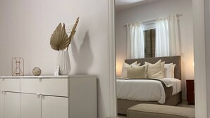 Un dormitorio con cama, mesita de noche y un espejo que refleja la habitación.