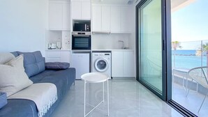 Een modern appartement met een zithoek, kitchenette en een balkon met uitzicht op zee.