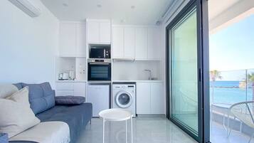 Un apartamento moderno con sala de estar, kitchenette y un balcón con vista al mar.