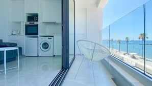 Een moderne keuken met inbouwapparatuur, een wasmachine en een eethoek met uitzicht op zee.