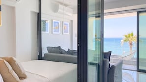 Quarto moderno com uma cama grande, um sofá e uma varanda com vista para o mar.