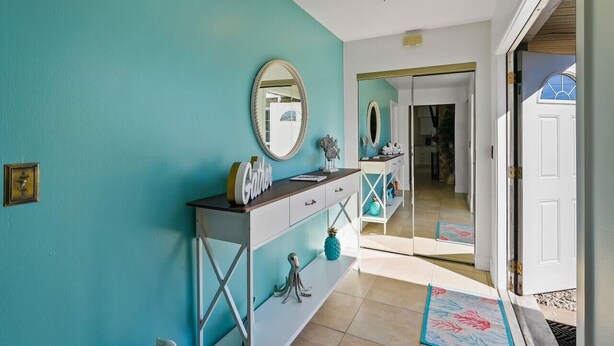 Een gang met turquoise wanden, een witte console tafel met spiegel, en een deur naar een andere kamer.