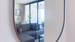 Un soggiorno moderno con un divano angolare grigio, un tavolino e un'ampia finestra con vista sull'esterno.