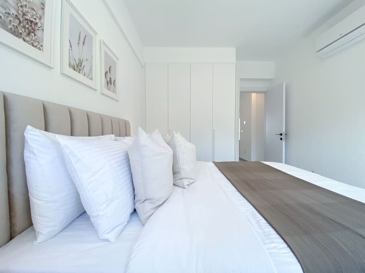 Een moderne slaapkamer met een groot bed, witte beddengoed en een houten vloer.