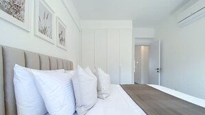 Una camera da letto moderna con un letto grande, biancheria da letto bianca e pavimento in legno.