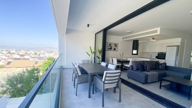 Un balcone moderno con zona pranzo, posti a sedere e vista sulla città.