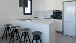 Una cucina moderna con isola centrale, sgabelli da bar, un frigorifero e una finestra.