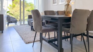 A modern dining area with a dark wooden table, six grey upholstered chairs, and a glass vase with dried plants on the table. - Phaedrus Living: Limnaria Luxury Flat Ivy 102 (Paphos)