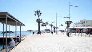 A paved promenade with palm trees, benches, and street lamps. - Phaedrus Living: Seaside Luxury Flat Lighthouse 67 (Paphos)