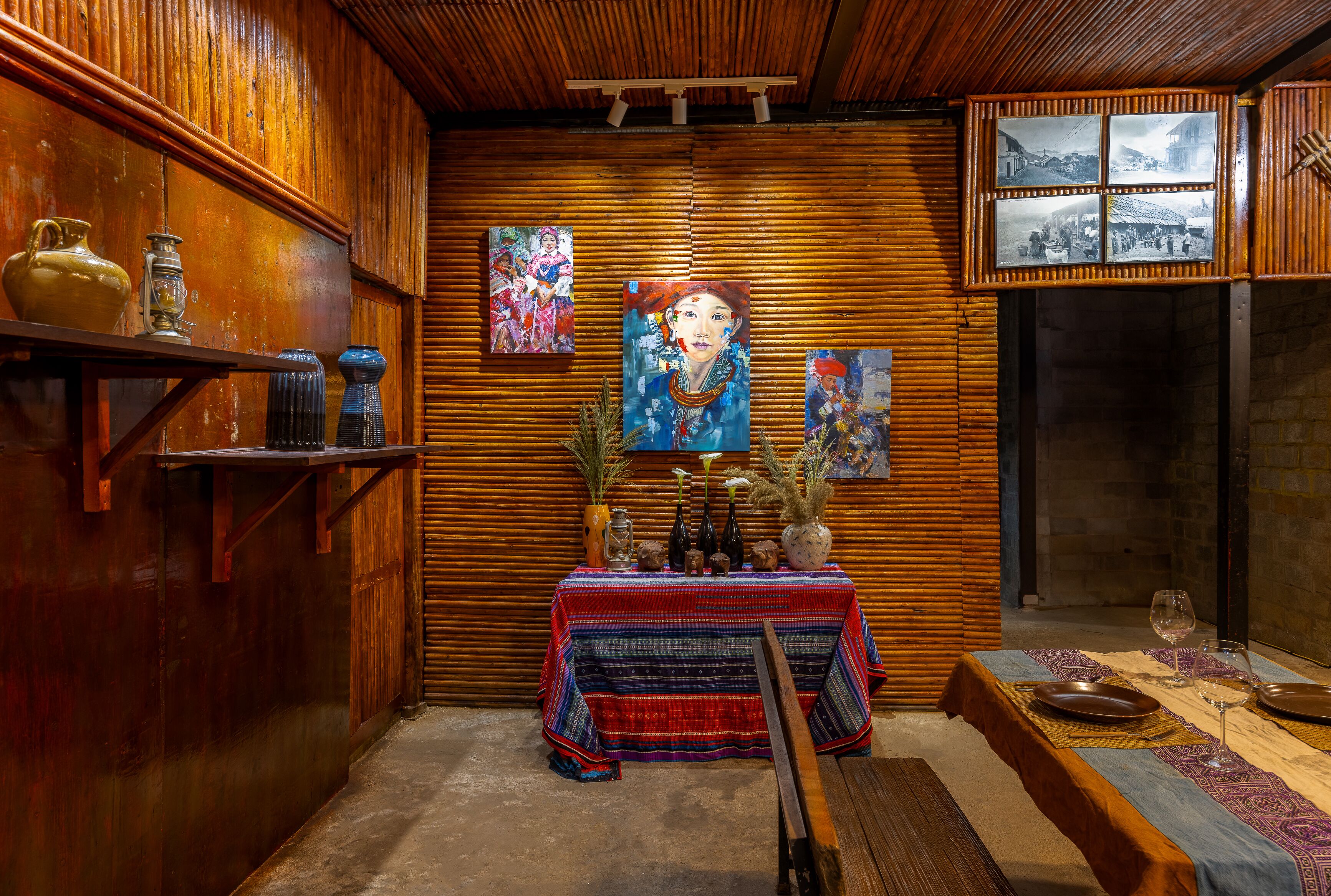 Un coin repas avec une table en bois dressée pour deux personnes, entouré d’œuvres d’art et d’une décoration rustique.