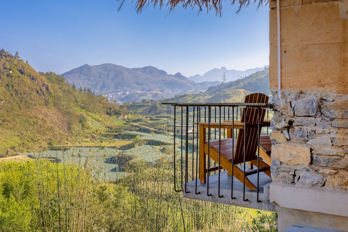Un balcón con vistas a campos en terrazas y montañas.