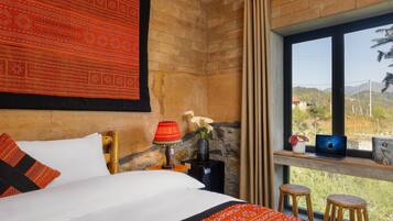 Habitación de hotel con cama, una laptop en el alféizar de la ventana, una lámpara y vistas al exterior.