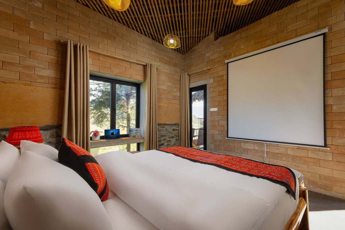Una habitación con una cama grande, una pantalla de proyector y una ventana con cortinas.