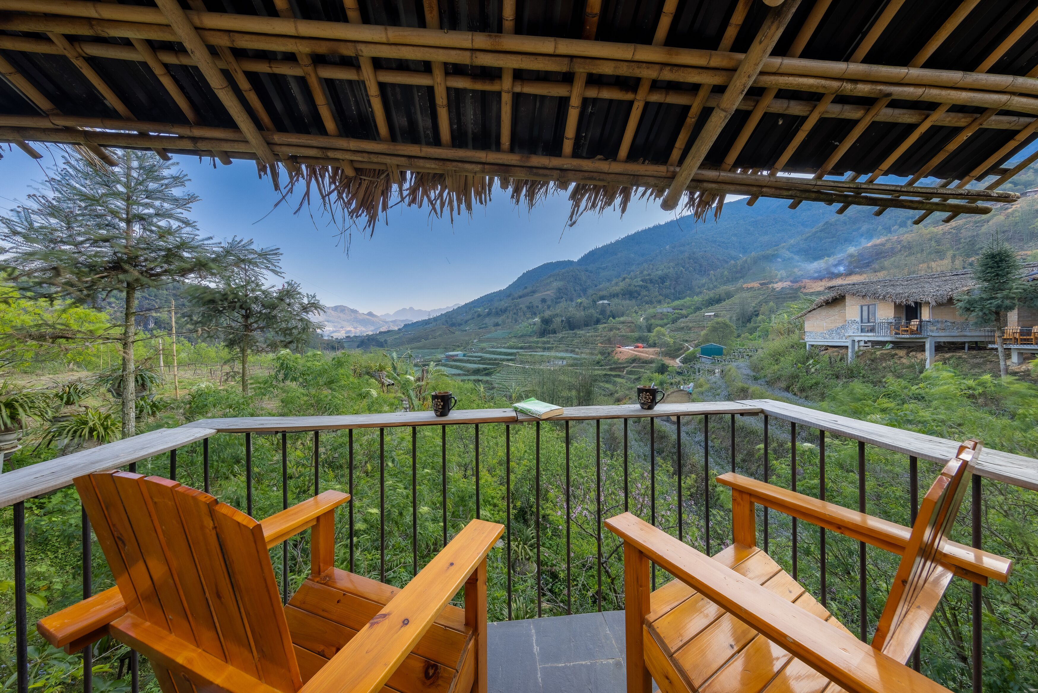 Terraza de madera con sillas que da a un valle exuberante y montañas.