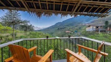 Terraza de madera con sillas que da a un valle exuberante y montañas.