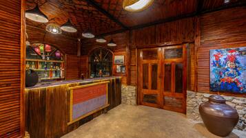 Interior de madera con una recepción, lámparas colgantes, un muro de piedra y un jarrón grande.