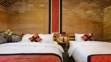 A hotel room with two beds, a stone wall, a wooden ceiling, and a red decorative strip.