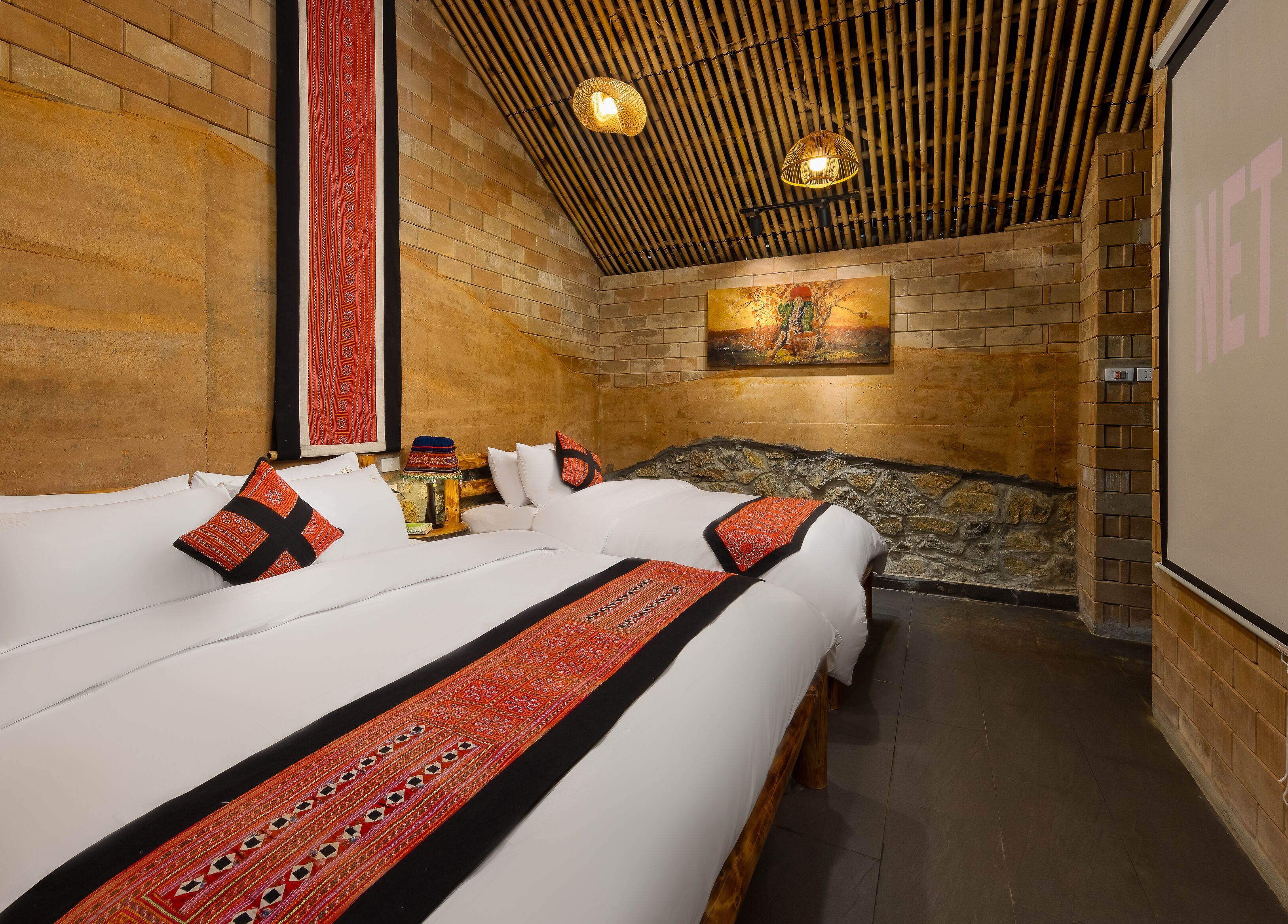 Ein Hotelzimmer mit einem großen Bett, einer Steinwand und einer Bambusdecke.