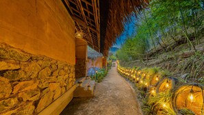 A pathway leading to a building with stone walls and a thatched roof. - Sapaxa Spring Garden Ecolodge (Ta Phin)