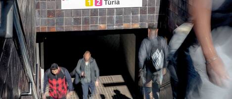 A subway entrance with a tiled wall and a sign indicating the station name.