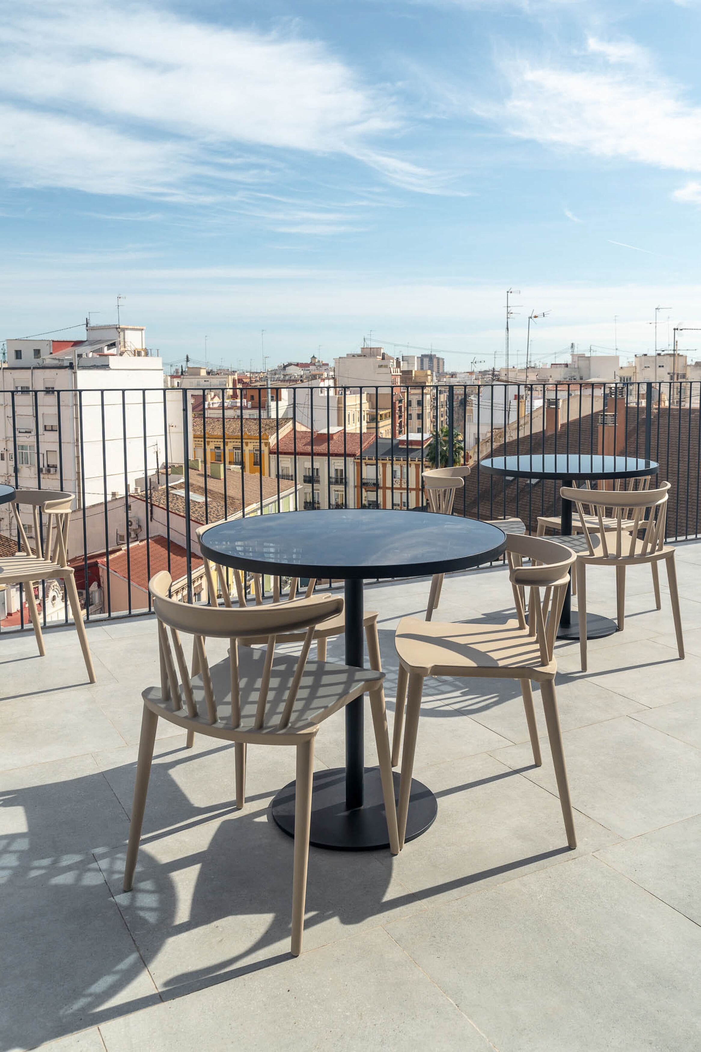 A rooftop terrace with a round table and chairs, offering a view of the cityscape.