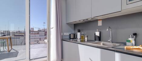 A modern kitchen with a large window, a sink, and a countertop with various items.