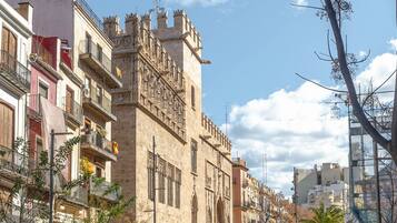 A historic building with ornate architecture, a paved plaza, and a clear sky.