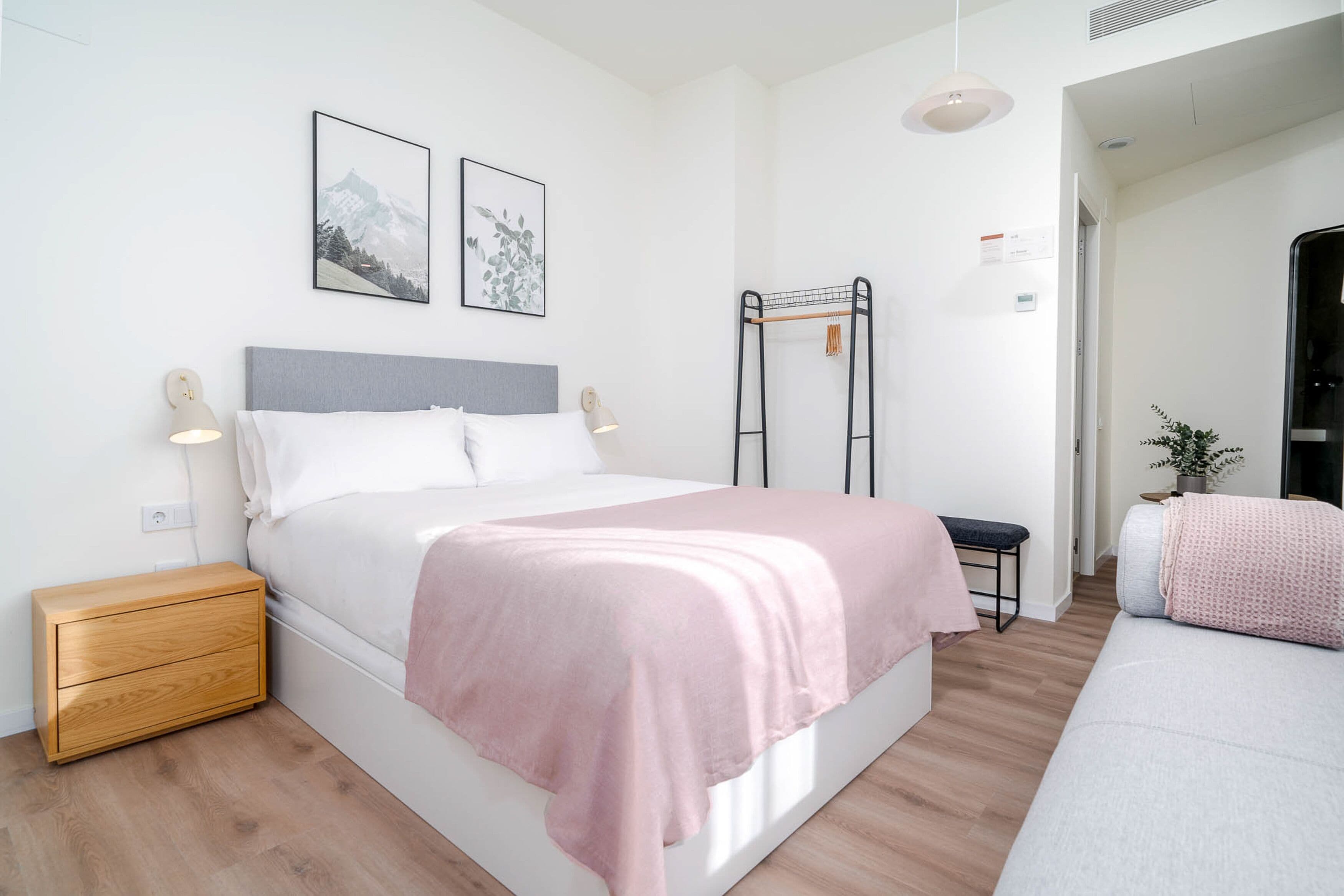 Un dormitorio moderno con cama, mesita de noche y un pequeño banco.