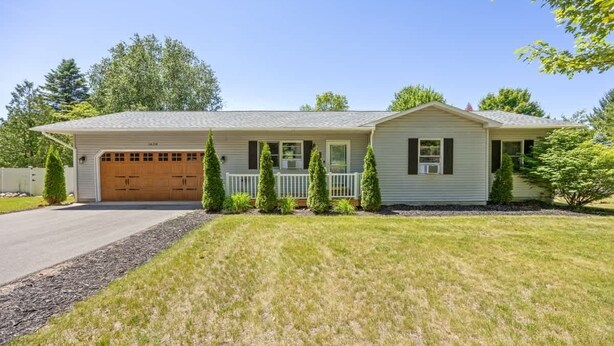 A single-story house with a garage, a front porch, and a well-maintained lawn. - Pet-friendly home with fenced-in yard and hot tub (Grawn)