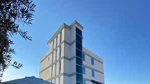 Zona de piscina con una silla colgante, sillones de descanso y un edificio al fondo.