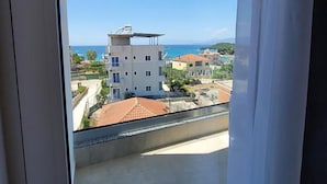 Un balcón con vistas despejadas a un pueblo costero, edificios y el mar.