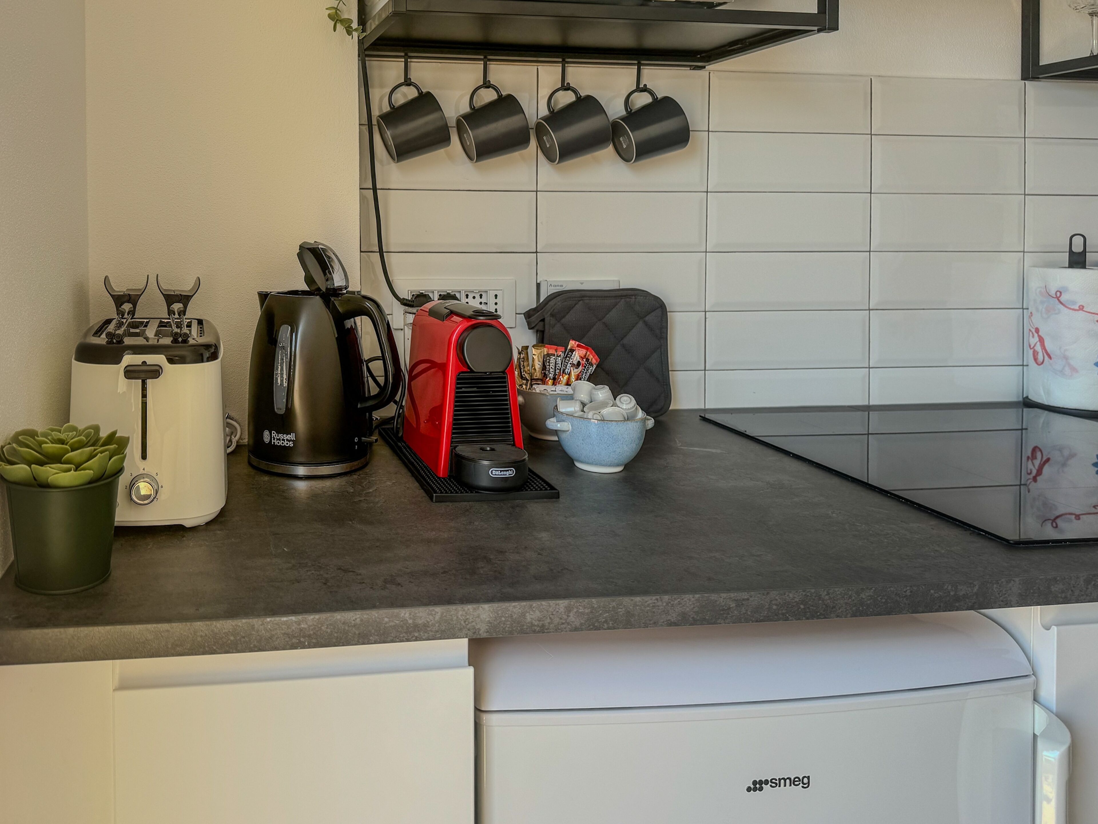 Una cucina con un tostapane, un bollitore, una macchina per il caffè e una ciotola di snack sul bancone.