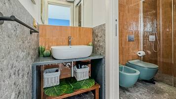 Un baño con lavamanos de mármol, ducha y retrete.