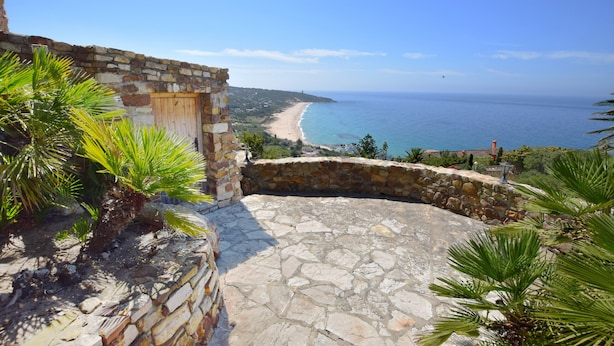 A stone pathway leading to a beach with a clear view of the ocean and a distant lighthouse. - Cosy villa with private swimming pool, magnificent views, for 6 PAX (Tarifa)