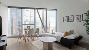 A modern living room with a large window, a dining area, a sofa, and a coffee table.