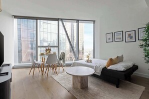 Ein modernes Wohnzimmer mit großem Fenster, Essbereich, einer Couch und einem Couchtisch.